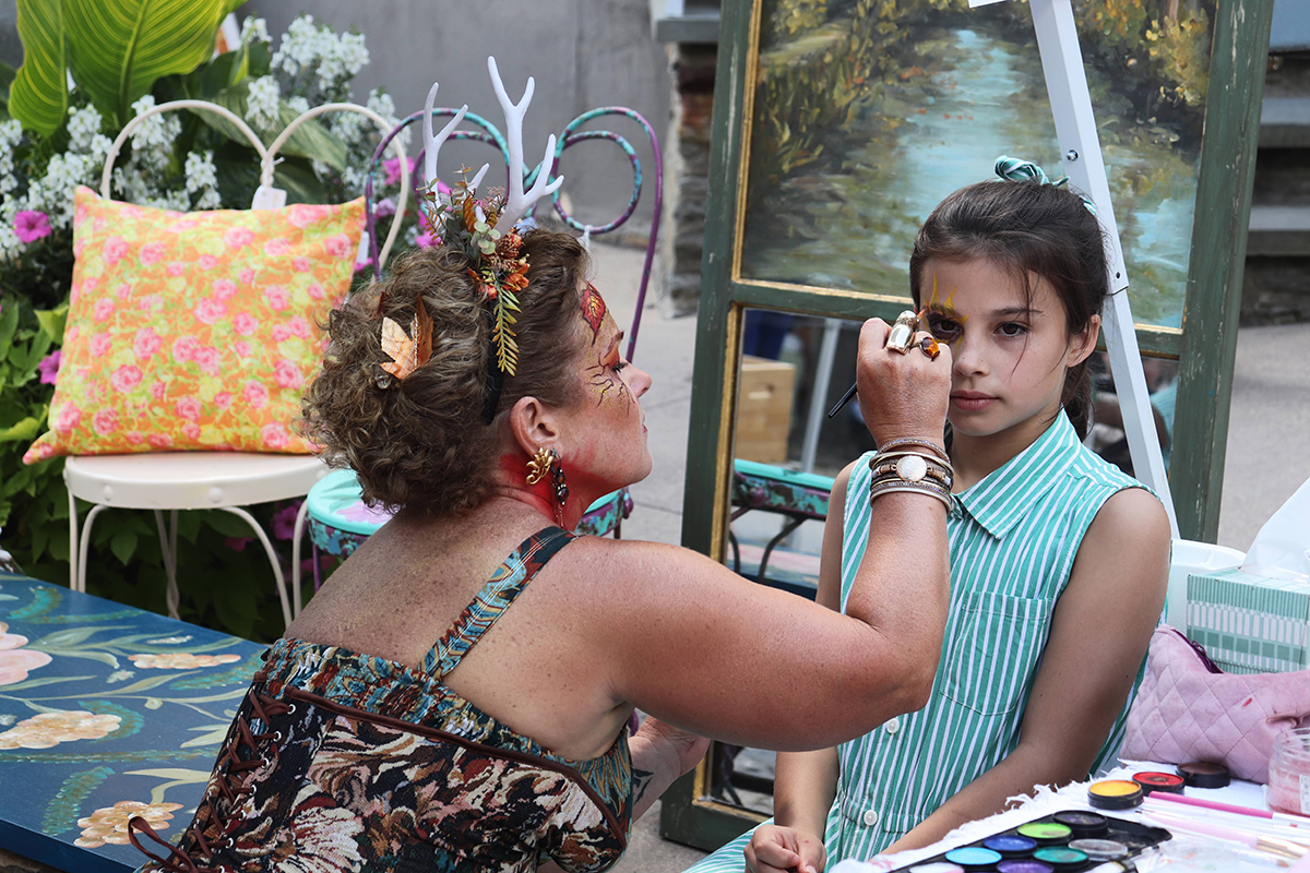 Artist painting a child's face at the Chestnut Hill Fall for the Arts Festival in Philadelphia